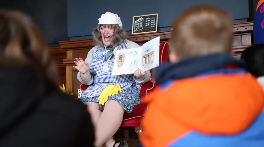 A person reads a story to children. They may be dressed as a cleaner